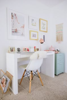 a white desk and chair in a small room with pictures on the wall above it