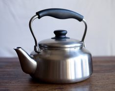 a silver tea kettle sitting on top of a wooden table