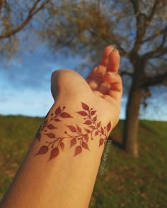 a person's arm with a tattoo on it and trees in the back ground