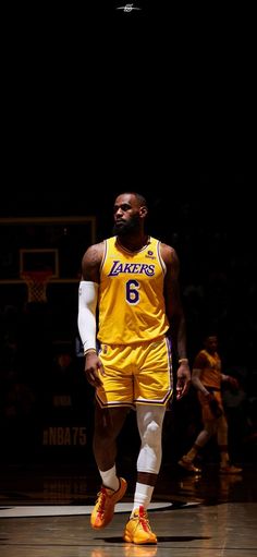 a basketball player in yellow and white uniform walking on the court with his foot up