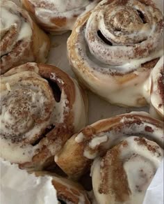 cinnamon rolls with icing sitting on top of white paper