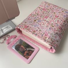 an open book, keychain, and photo frame on a white table next to a camera