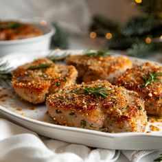 some meat on a white plate with herbs and seasoning sprinkled around it