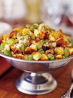 a silver bowl filled with stuffing on top of a wooden table