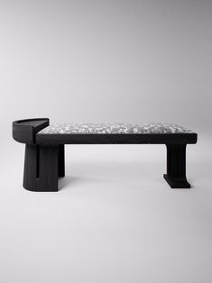 a black bench sitting on top of a white floor in front of a gray wall