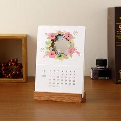 a desk calendar sitting on top of a wooden table next to some books and other items