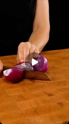 a person cutting onions with a knife on a wooden table