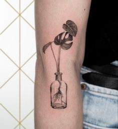 a black and white photo of a flower in a bottle with water on the arm