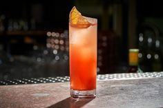 a tall glass filled with an orange drink