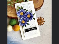 a card with blue flowers on it next to some green balls and wood slicers