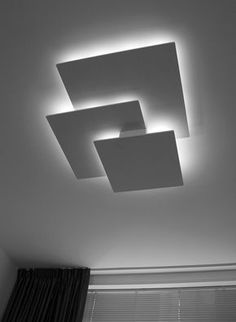 two square lights are suspended from the ceiling in a room with black and white curtains