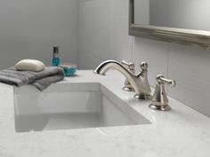 a bathroom sink with two faucets and towels on the counter top next to it