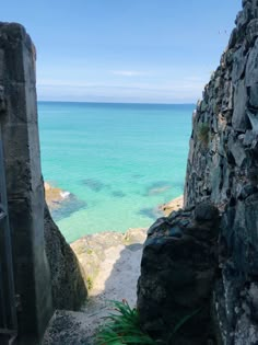 an open door leading to the ocean from a cliff side area with blue water in the background