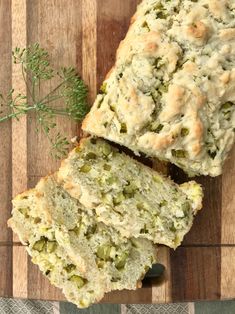 a loaf of bread on top of a wooden cutting board next to a sprig of green herbs