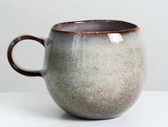 a white and brown coffee cup sitting on top of a table