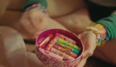 a person holding a cup filled with lots of pencils and crayons in it