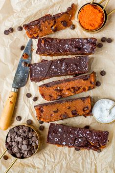 several pieces of brownie sitting on top of a table next to bowls of chocolate chips