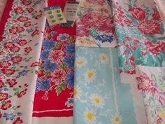 several different types of cloths laid out on a white tablecloth with red, blue and yellow flowers