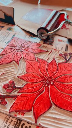 a close up of a piece of paper with red flowers on it next to a pair of scissors