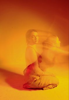 a man sitting on the ground in front of a yellow background