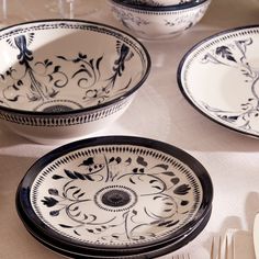 four black and white plates on a table with utensils in front of them