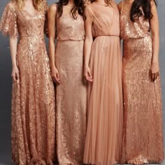 four women in long dresses posing for the camera with one woman wearing a pink dress