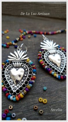 two pieces of jewelry are sitting on a table with beaded beads around them and the words de la luz artisan written in spanish