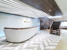 an office lobby with a curved reception desk and wooden staircase leading up to the second floor