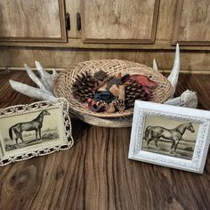 three framed pictures and two deer antlers are sitting on a table in front of a basket