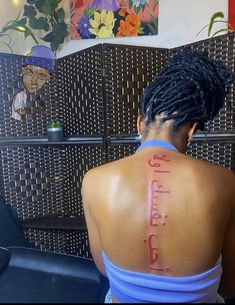 the back of a woman's head with writing on her upper arm and chest