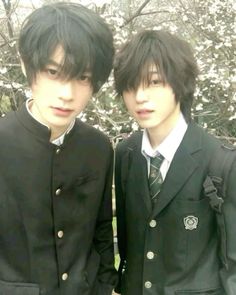 two young men standing next to each other in front of a tree with white flowers