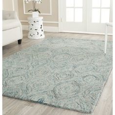 a large blue rug in the middle of a living room with white furniture and flowers