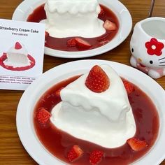 two white plates with strawberry cream cake on them and a hello kitty mug in the background