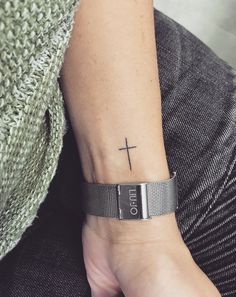 a person with a cross tattoo on their wrist