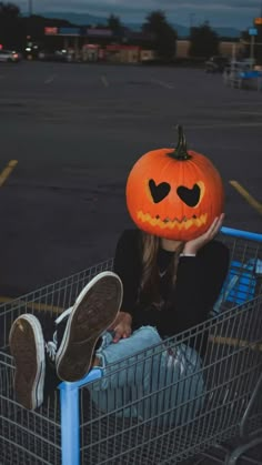 a woman sitting in a shopping cart with a pumpkin on her head and eyes drawn out