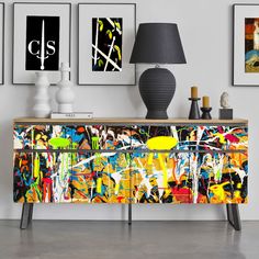 an abstract painting is on the sideboard next to two lamps