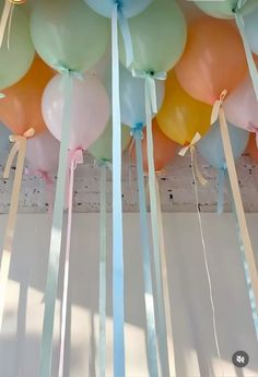 many balloons are hanging from the ceiling with ribbons