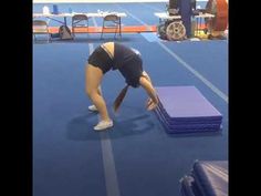 a woman bending over while standing on top of a blue mat