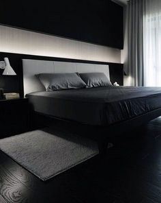 black and white photo of a bedroom with a bed, night stand, rug and lamp