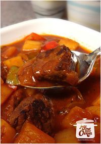 a spoon full of stew with meat and vegetables