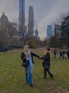 two women are walking in the park with their arms around each other and holding hands