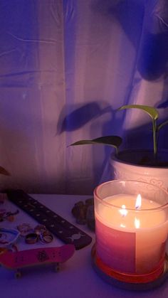 a lit candle sitting on top of a table next to a skateboard and plant