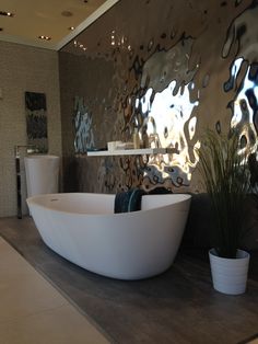 a large white bath tub sitting on top of a bathroom floor next to a plant