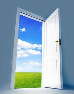 an open door leading to a green field with blue sky and clouds in the background