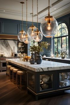 a kitchen with marble counter tops and pendant lights hanging from the ceiling over the island