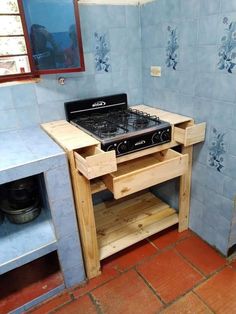 a stove top oven sitting inside of a kitchen next to a blue tiled wall and floor