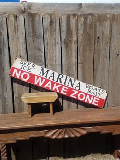 there is a sign that says beer marina and no wake zone on the bench next to it