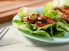 lettuce wraps filled with meat and vegetables on a plate next to a fork