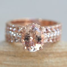 a ring with an oval shaped morganite surrounded by smaller round diamonds on top of it