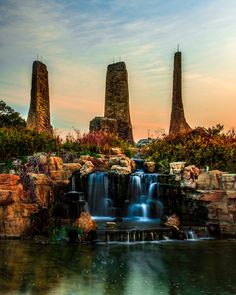 there is a waterfall in the middle of some rocks and water with two tall towers behind it